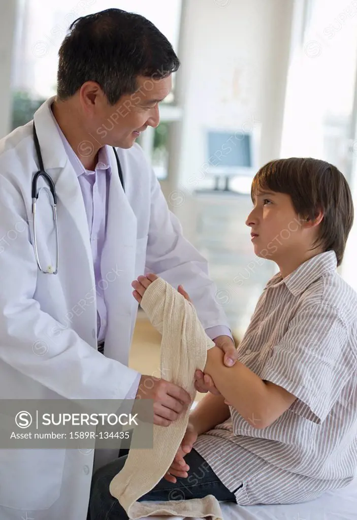Doctor wrapping boy´s hand with bandage in examination room