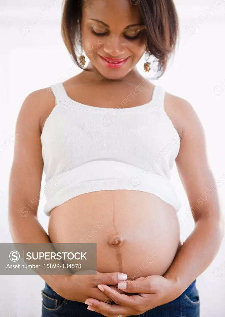 Smiling pregnant Black woman holding stomach