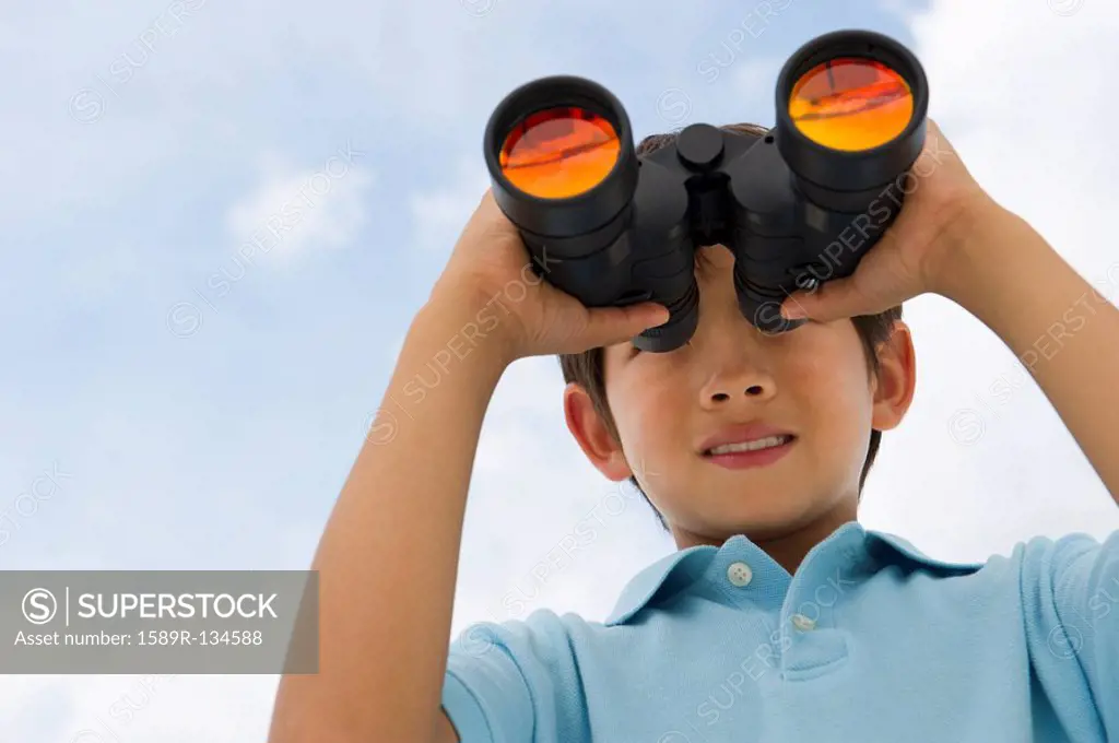 Mixed race boy looking through binoculars