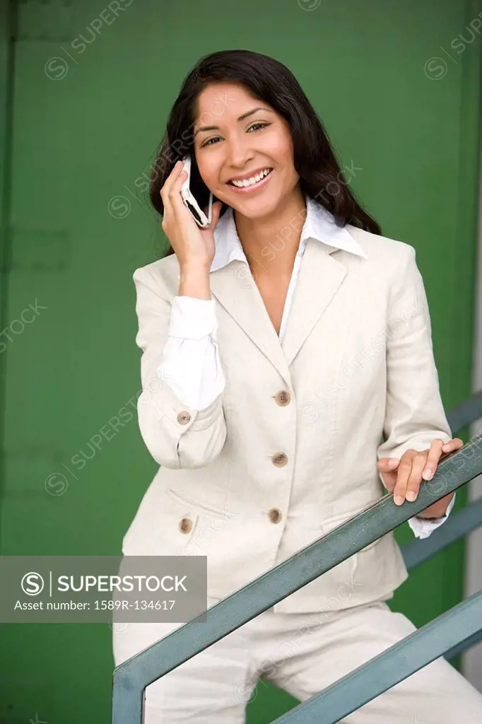 Smiling Hispanic businesswoman talking on cell phone