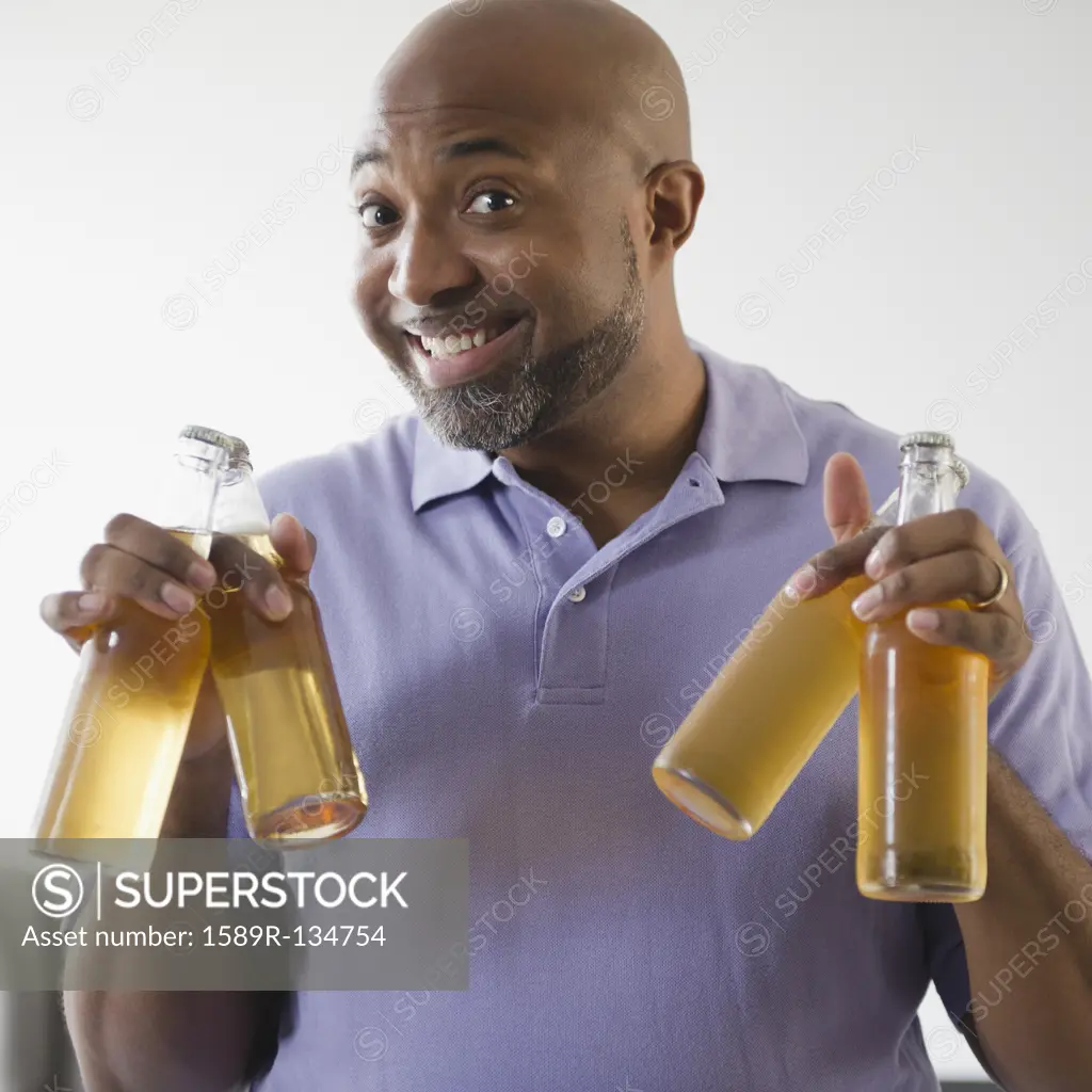 Smiling African American man holding beer bottles