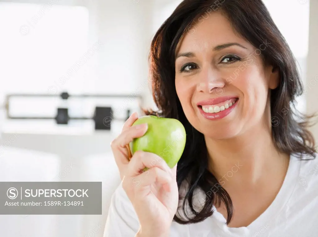 Smiling Hispanic woman holding a green apple