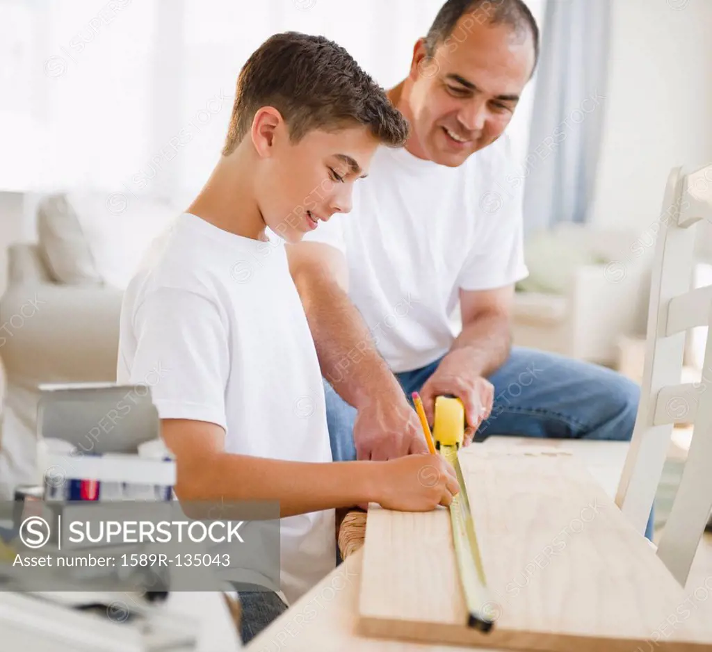 Hispanic father teaching his son carpentry