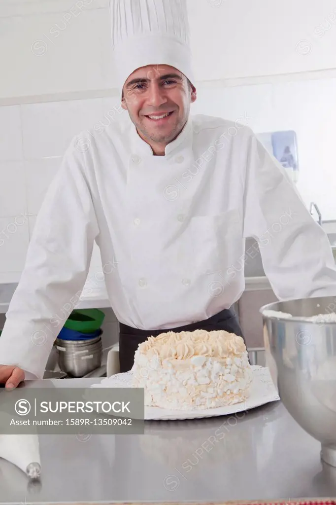 Smiling Hispanic chef posing with cake