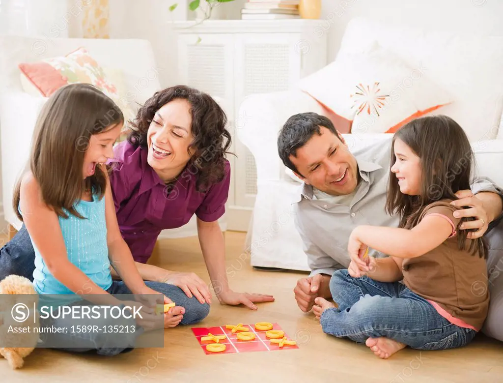 Father and mother playing game in livingroom with children