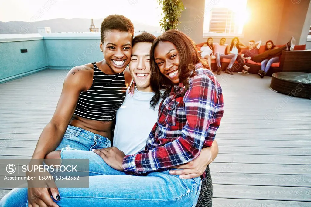 Portrait of smiling women on lap of man on rooftop