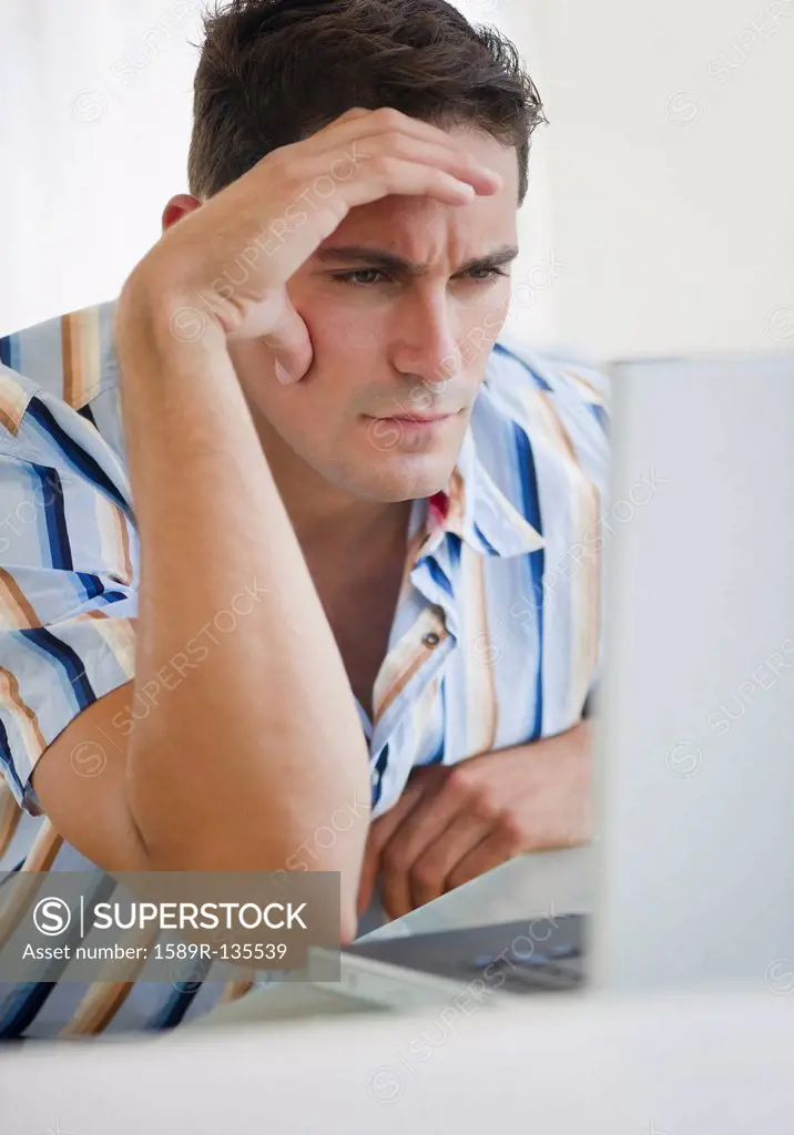 Frustrated mixed race businessman frowning at laptop