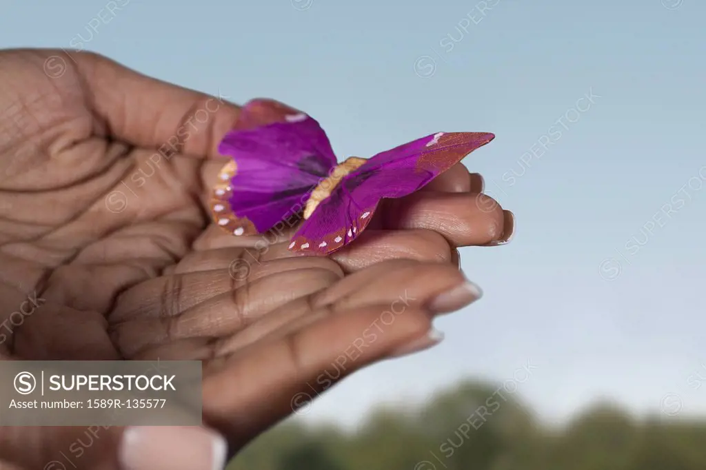 Black woman´s hands holding purple butterfly