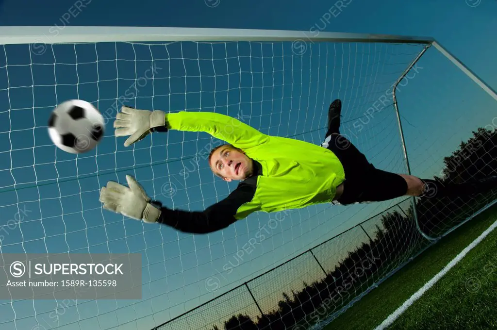 Caucasian goalie deflecting soccer ball