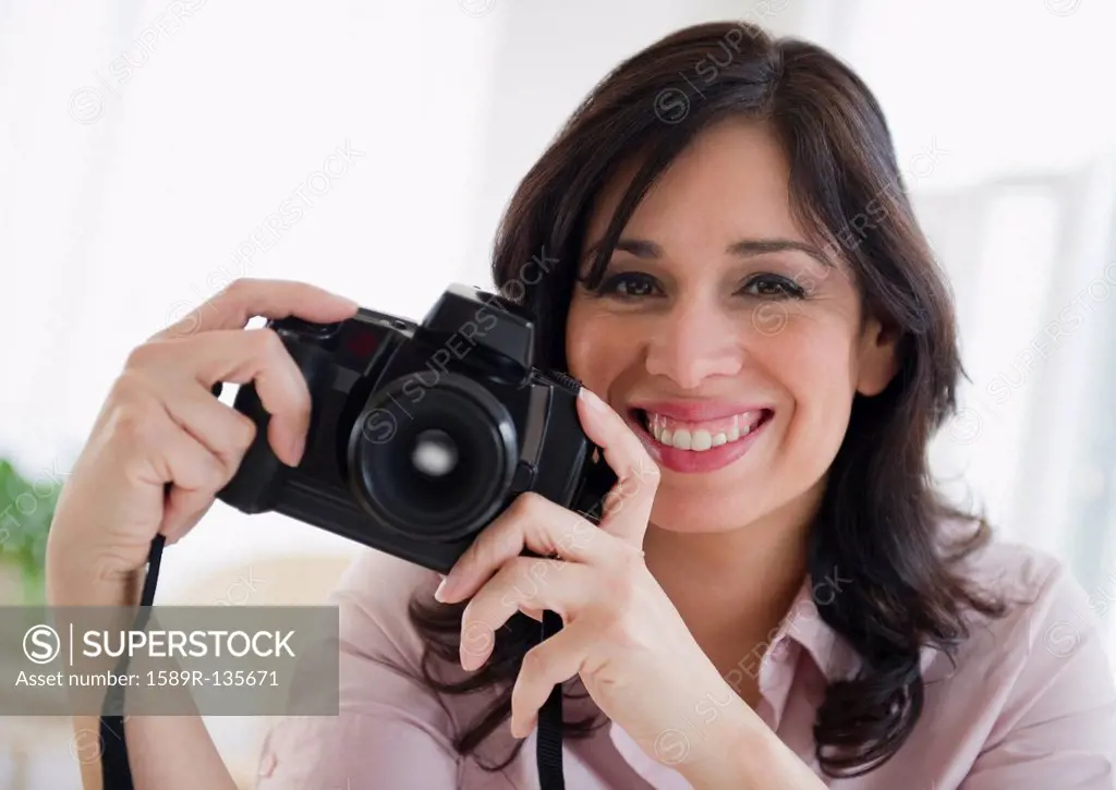 Smiling Hispanic woman holding digital camera