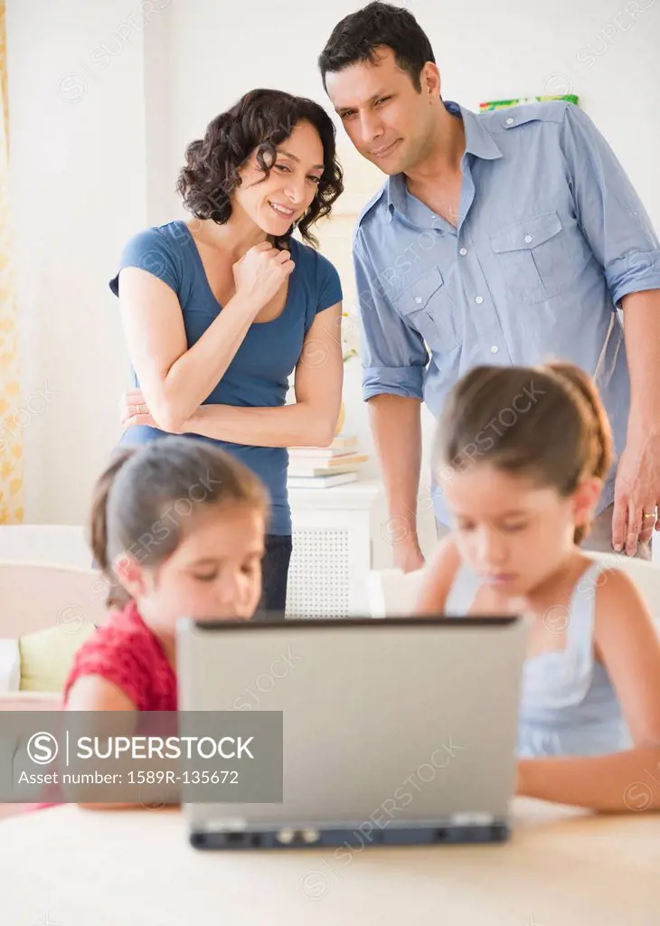 Father and mother watching children using internet together