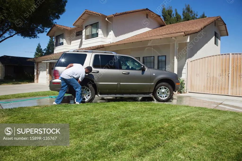 Black man washing car in driveway