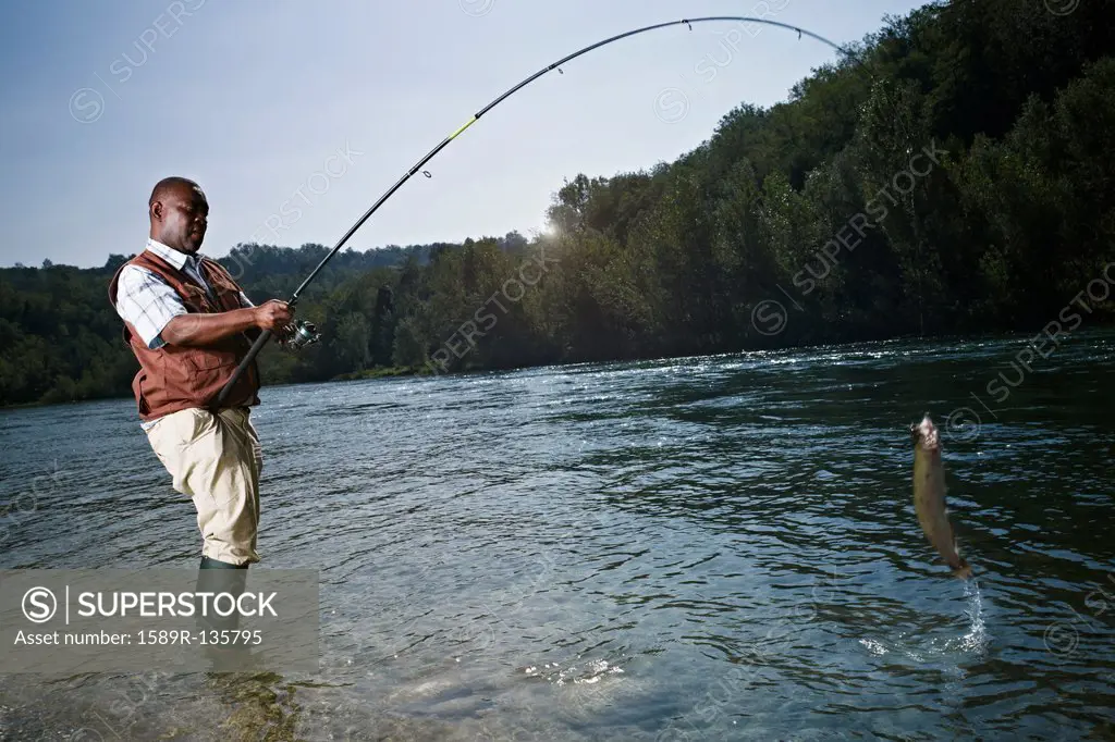 Black man catching fish in stream