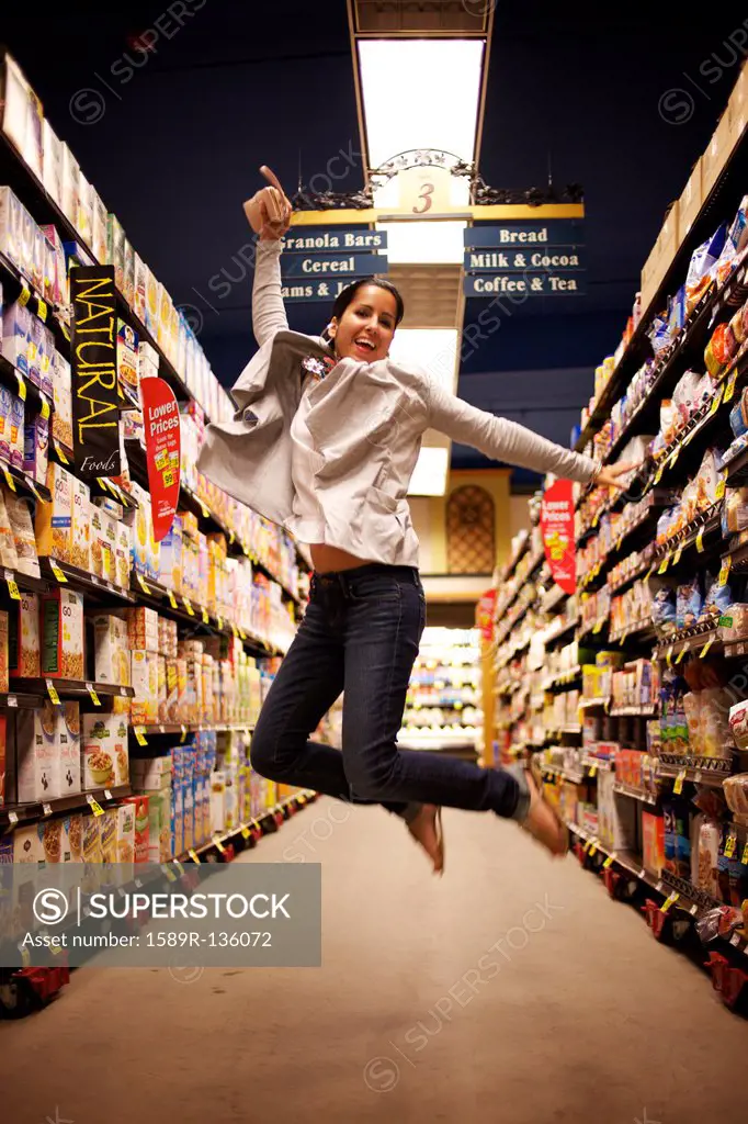 Hispanic woman jumping in grocery store