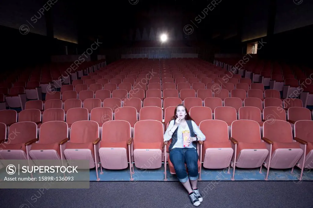 Caucasian woman watching move in empty theater