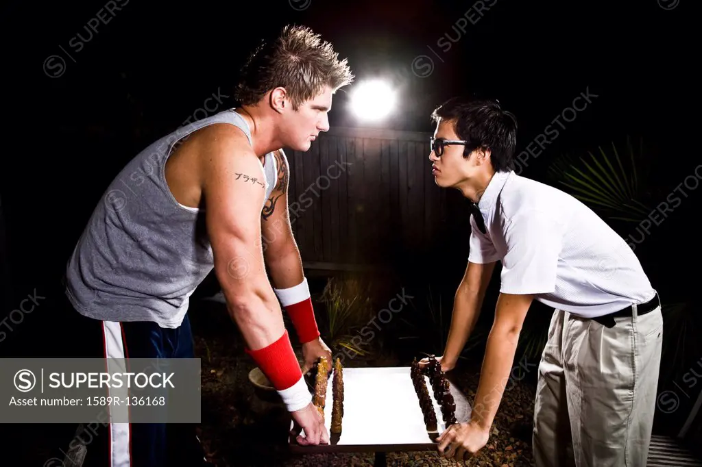 Geek and body builder playing chess