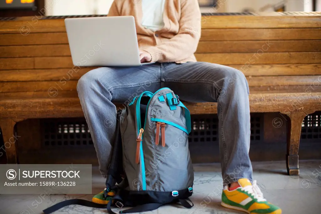 Caucasian man sitting on bench using laptop