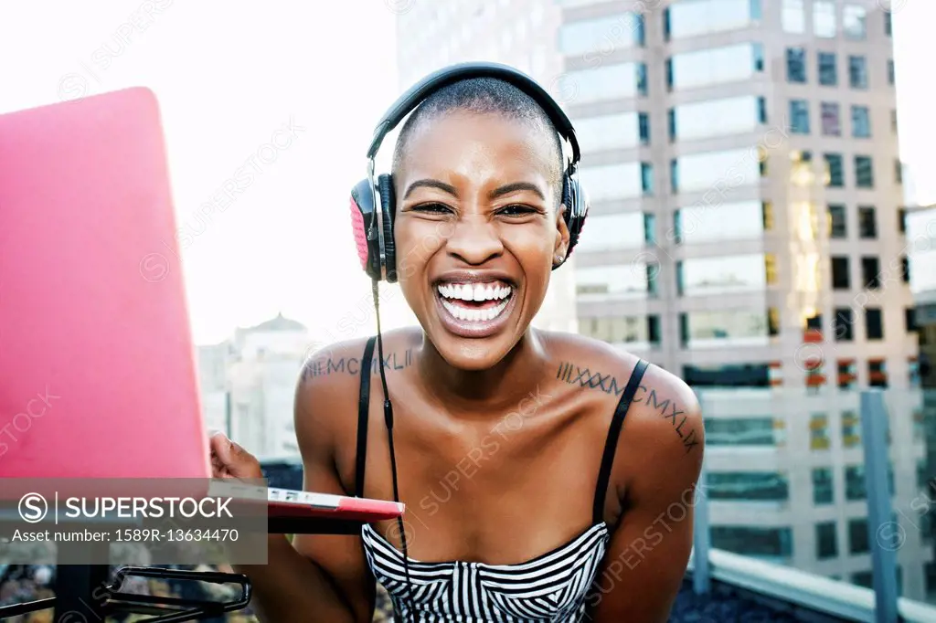 Portrait of Black DJ laughing on urban rooftop
