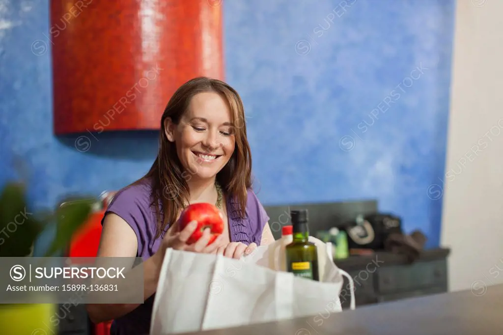 Pregnant Caucasian woman unpacking groceries in kitchen