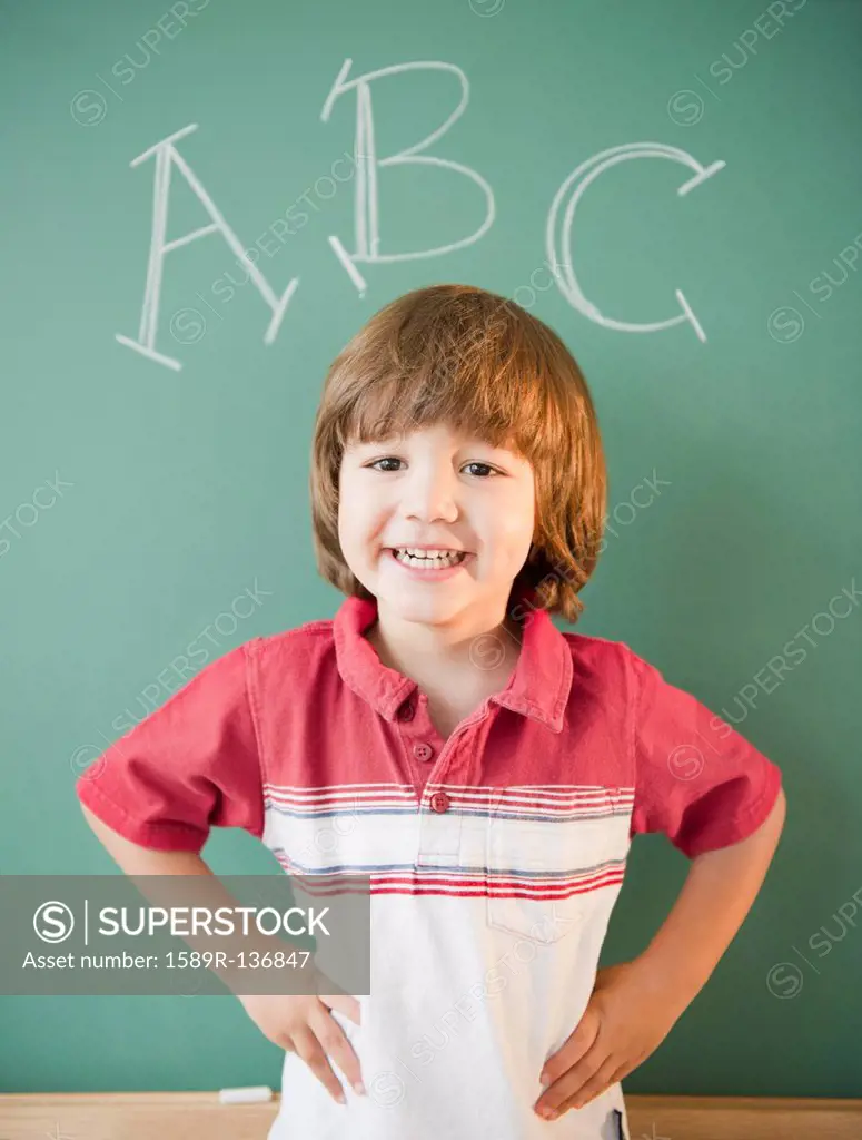 Hispanic boy standing underneath abc´s on blackboard