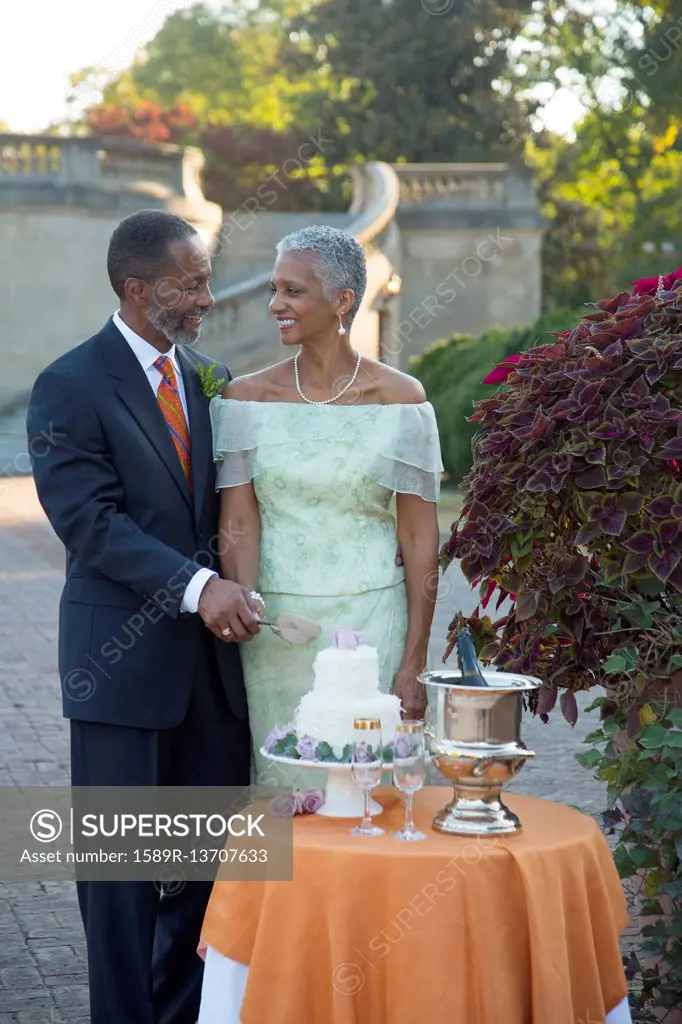 Black couple cutting wedding cake