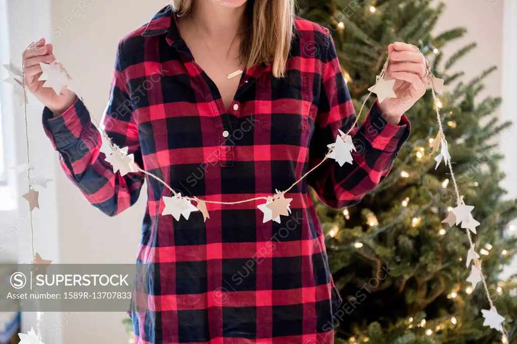 Caucasian woman holding Christmas ornaments on string
