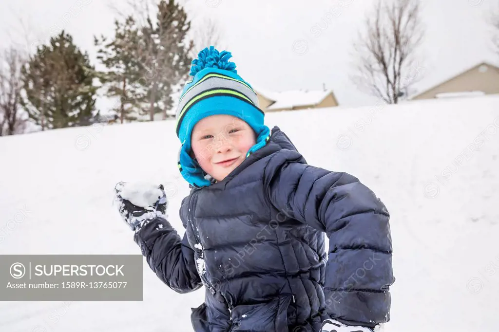 Smiling boy throwing snowball in winter