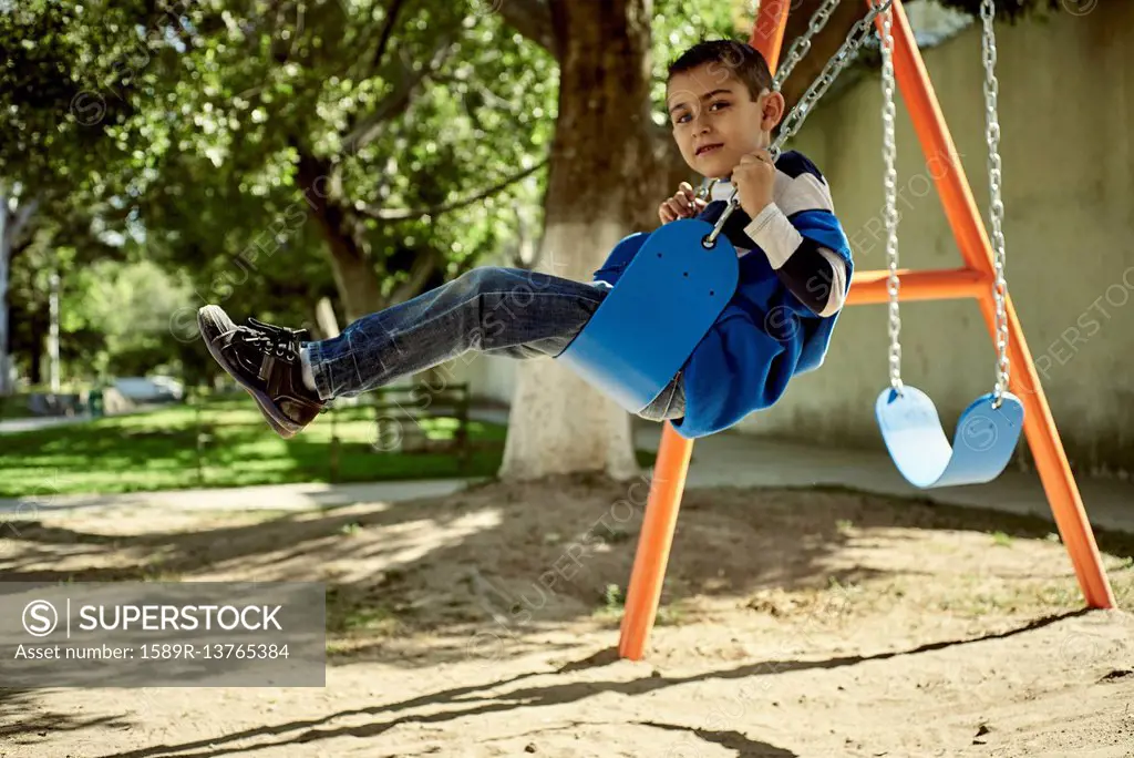 Hispanic boy on swing at park