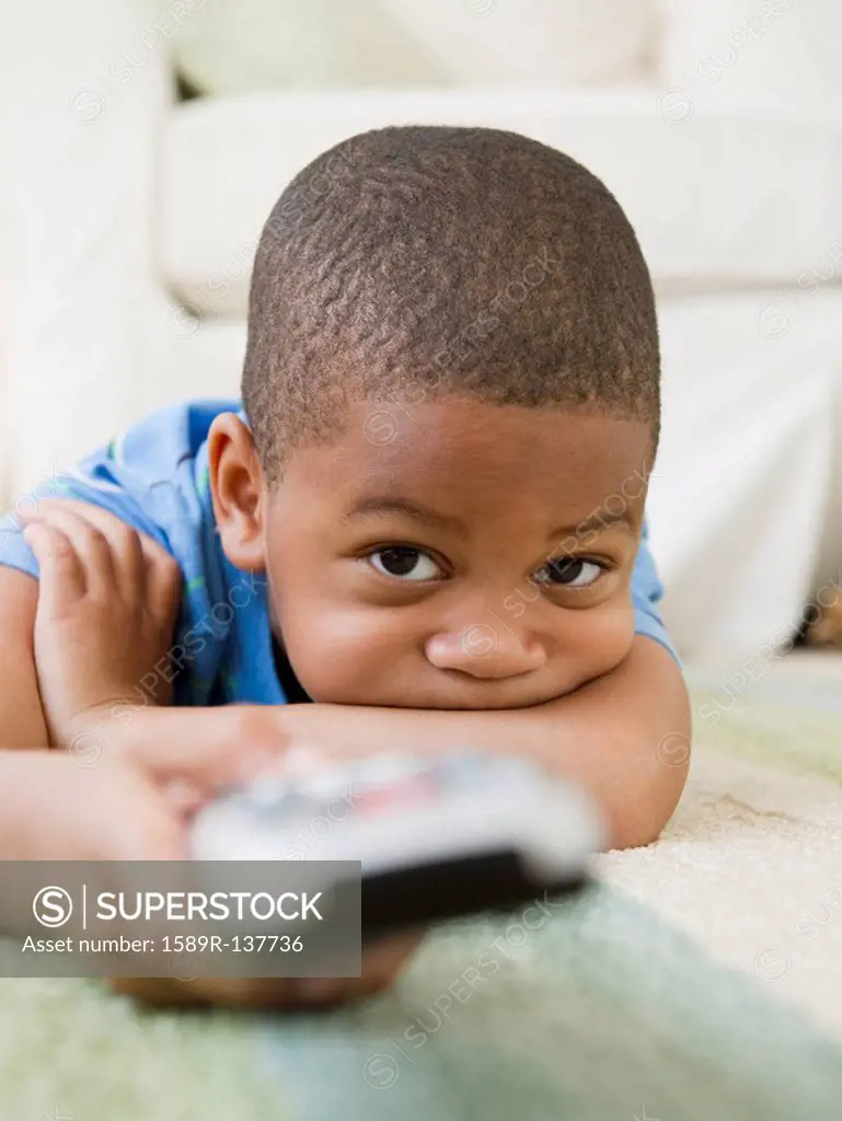 African American boy laying on floor watching television