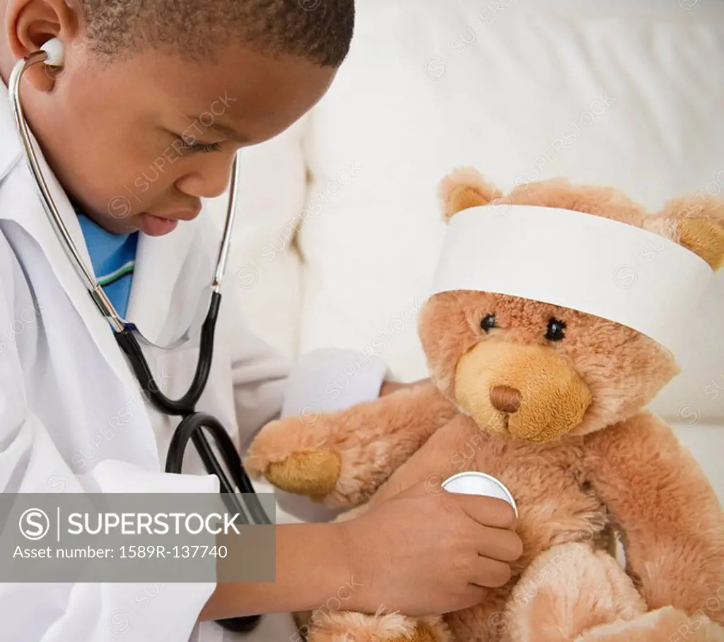 African American boy playing doctor with teddy bear