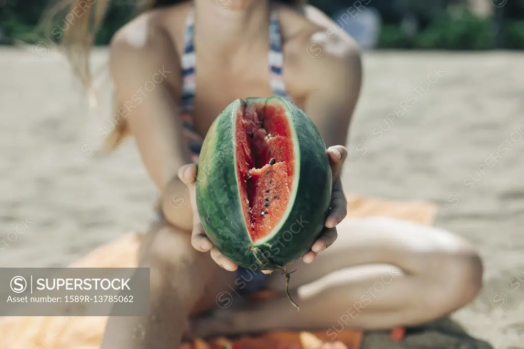 Caucasian woman showing sliced watermelon on beach