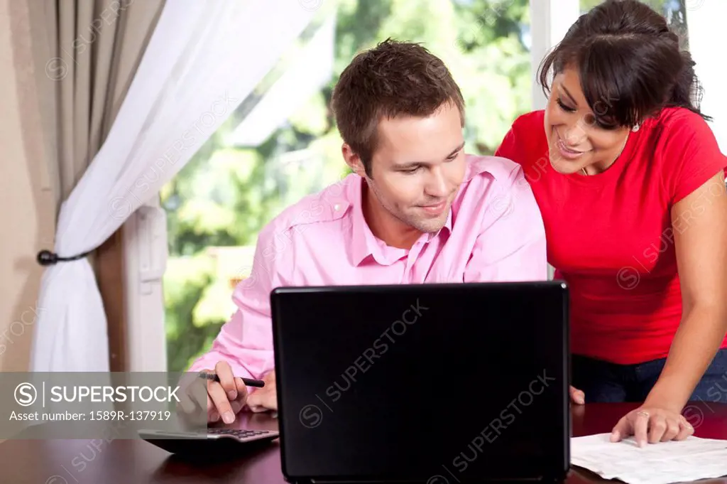 Couple paying bills and using laptop and calculator