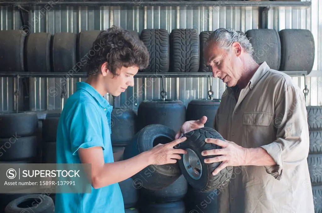 Hispanic grandfather and grandson looking at go_cart tires