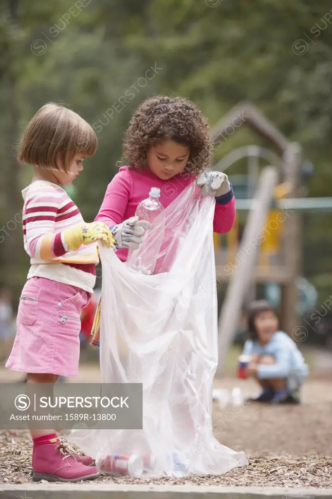 Two girls picking up trash in park