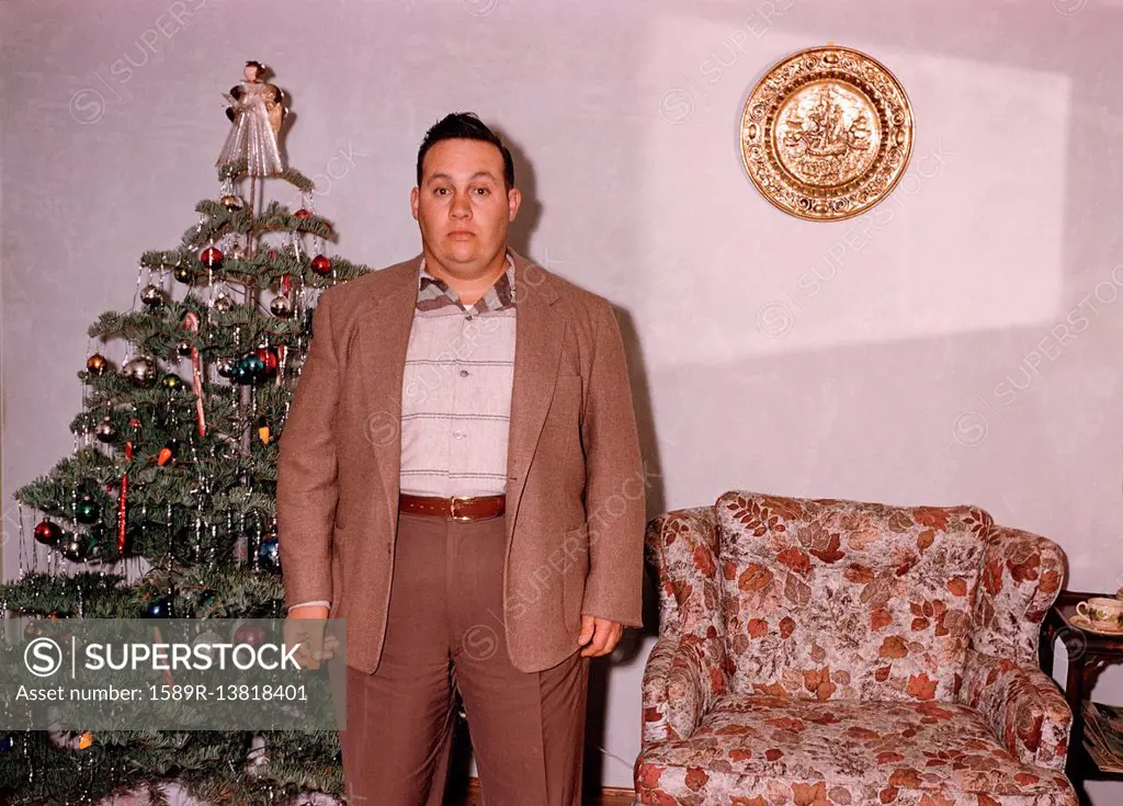Serious Caucasian man posing near Christmas tree