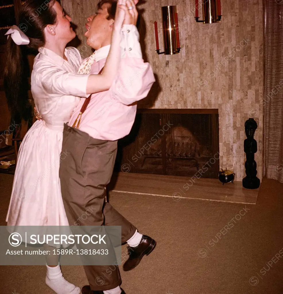 Caucasian man and woman dancing near fireplace