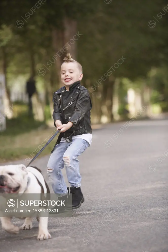 Boy with mohawk in leather jacket walking dog