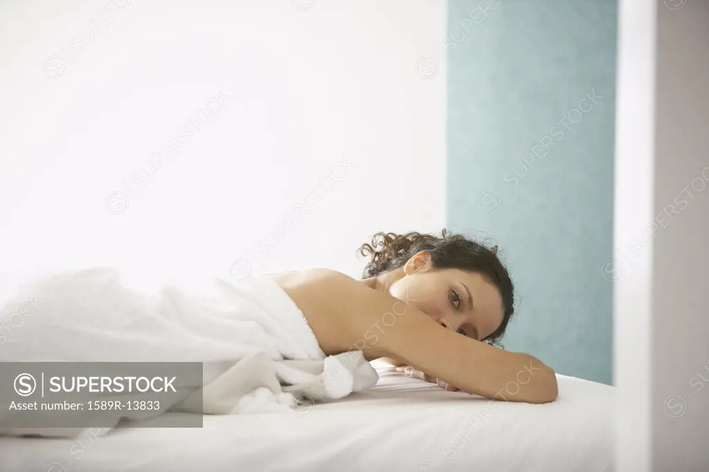 Portrait of woman wrapped in towel laying on bed