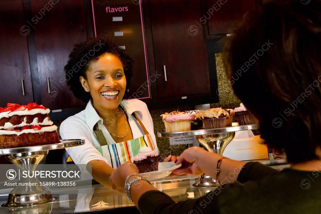 African American bakery owner serving customer cupcake