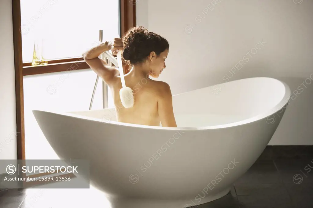 Rear view of woman bathing in tub
