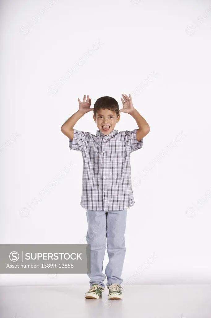 Portrait of boy sticking tongue out and gesturing with hands