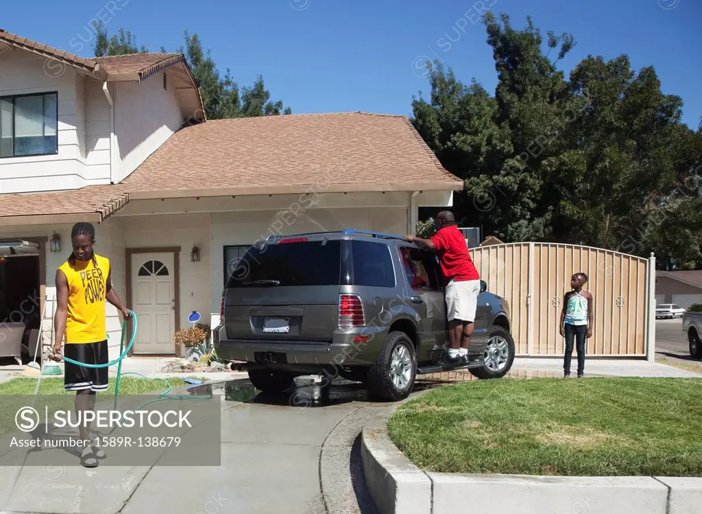 Black family washing car in driveway
