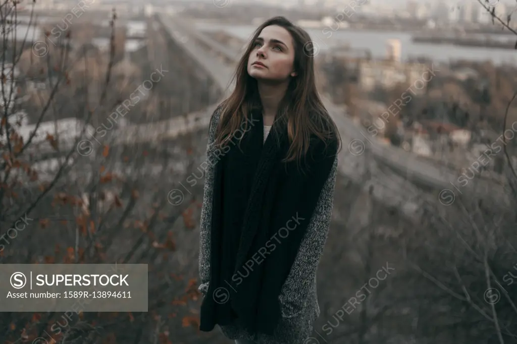 Portrait of pensive Caucasian woman standing on hill near freeway