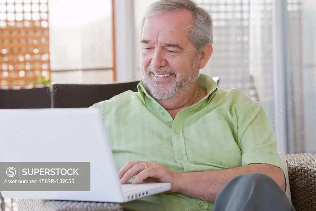 Senior Chilean man typing on laptop