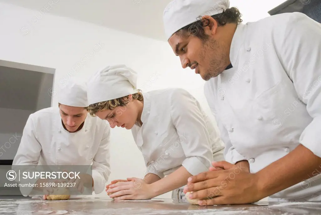 Bakers working with dough in bakery kitchen