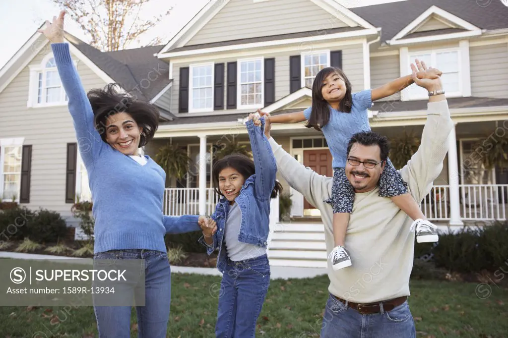 Portrait of family jumping in front yard
