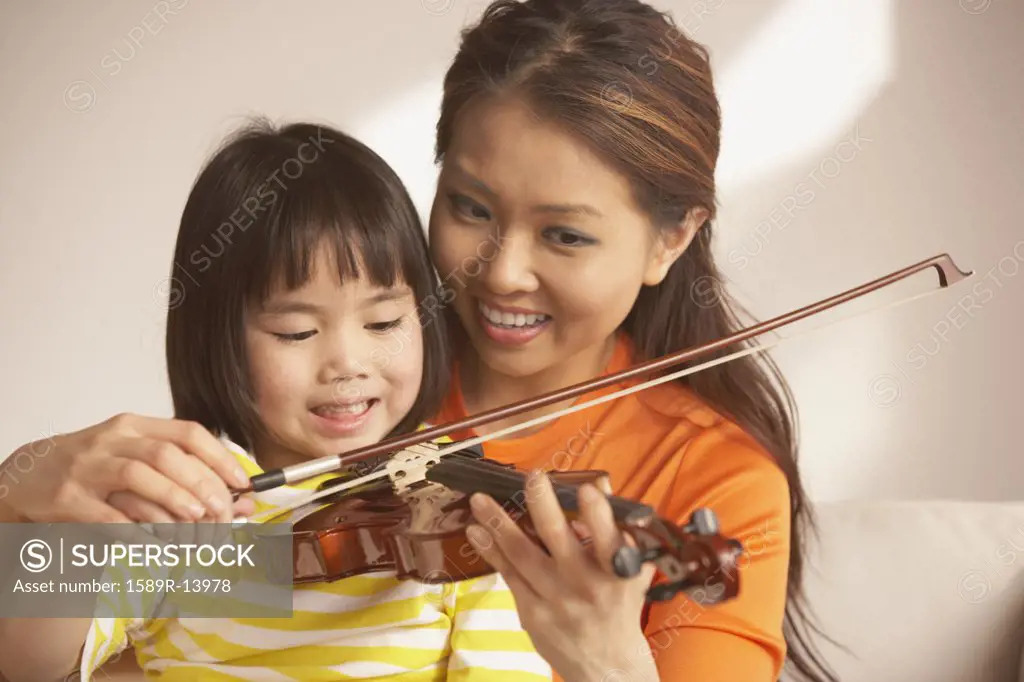 Mother helping her daughter play the violin