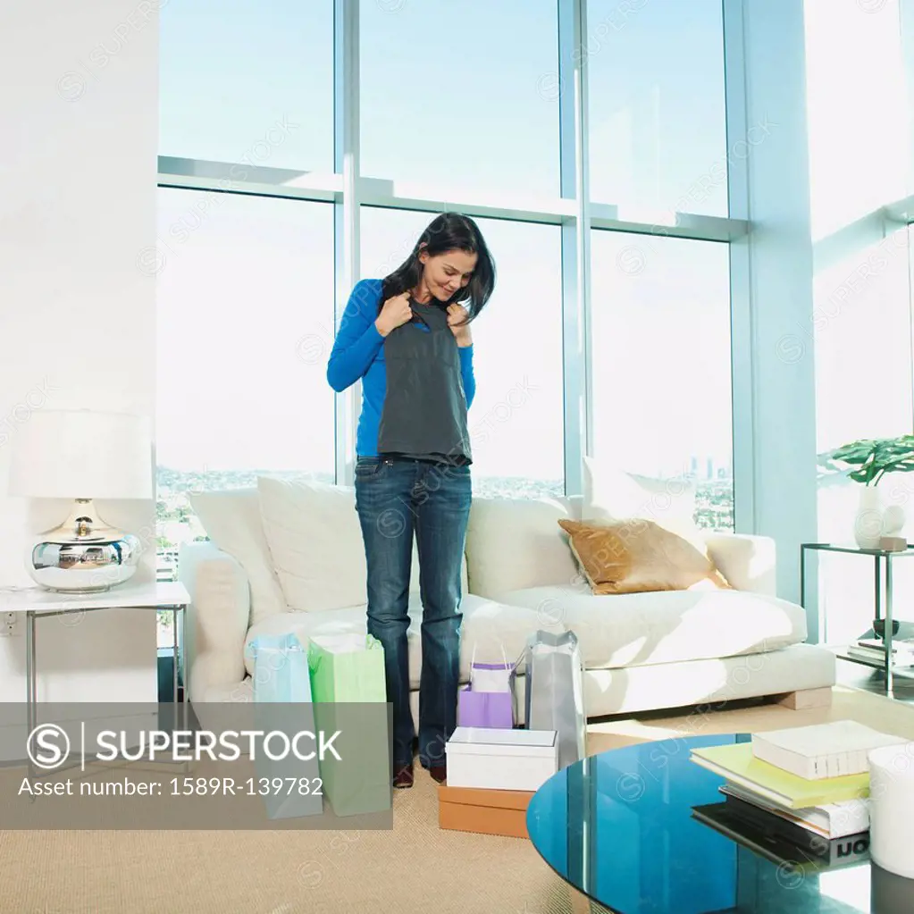 Mixed race woman looking at clothing in living room