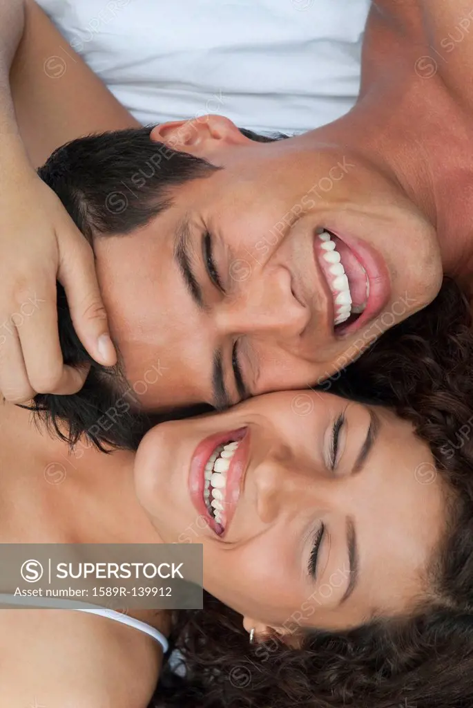 Laughing Hispanic couple laying together