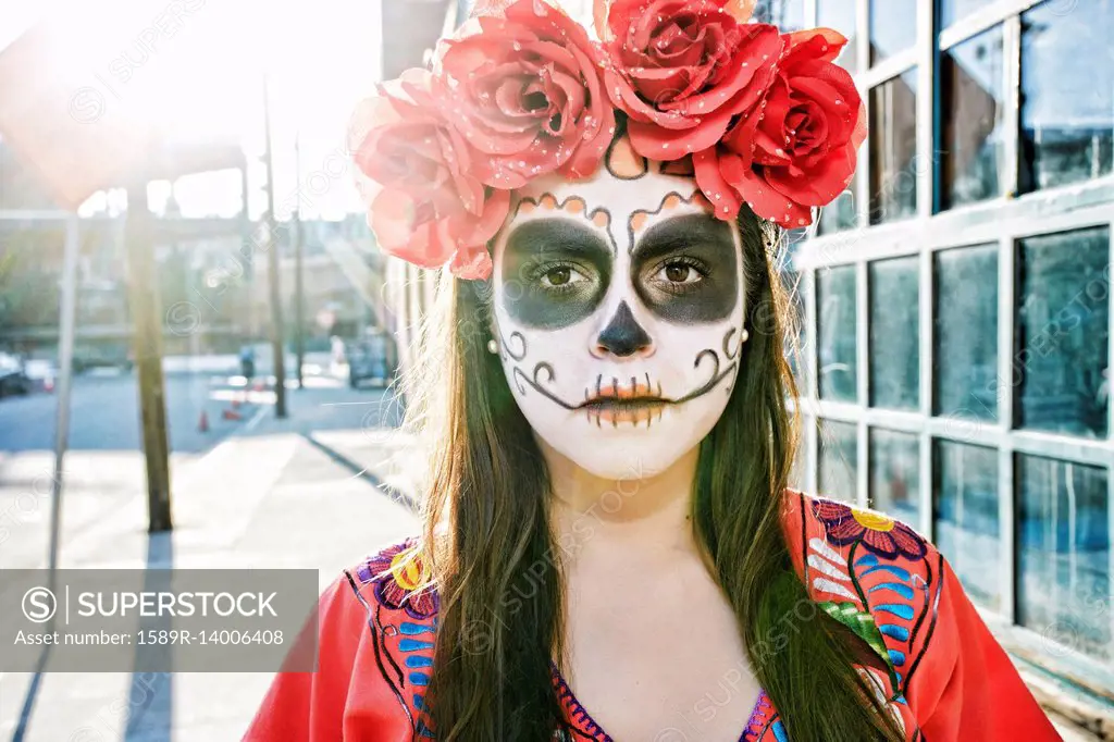 Hispanic woman on sidewalk wearing skull face paint